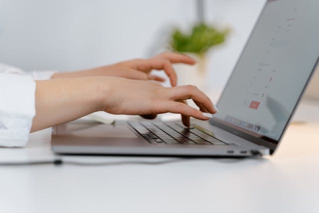 Person typing on a grey laptop