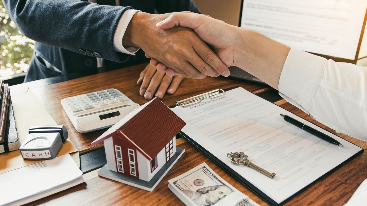 Two people shaking hands over documents