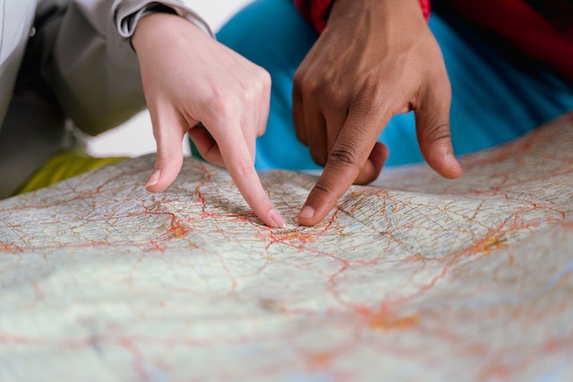 two people pointing to the same place on a map