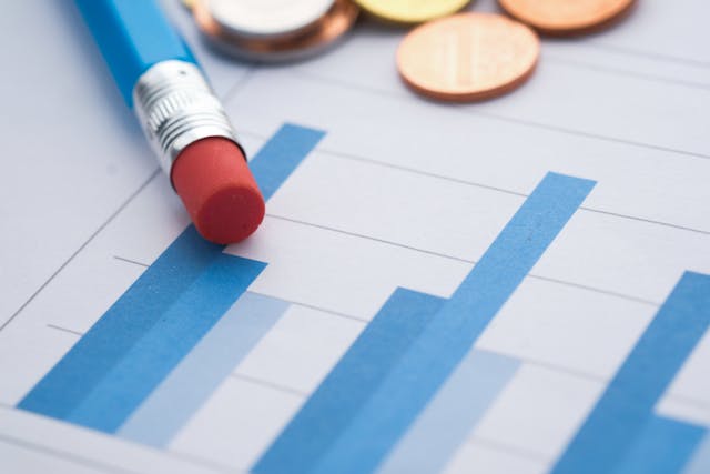 a blue bar chart with coins and pencil resting on top