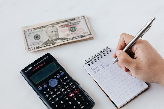 a calculator a stack of money and a person making a budget