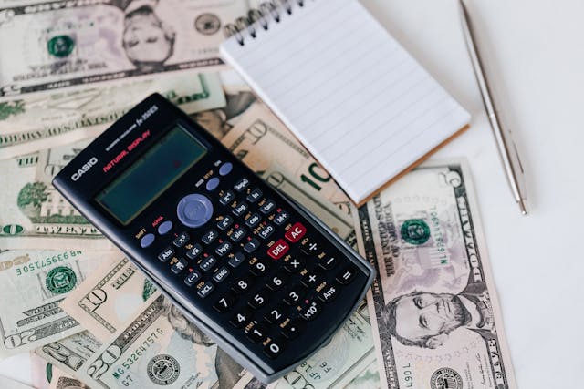 a calculator and notepad on a bunch of cash