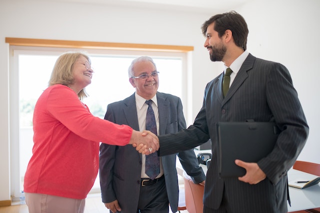 a real estate expert shaking hands with a couple buying a home