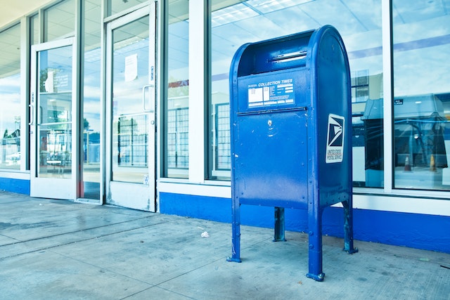 blue American postal service mailbox outside of a store