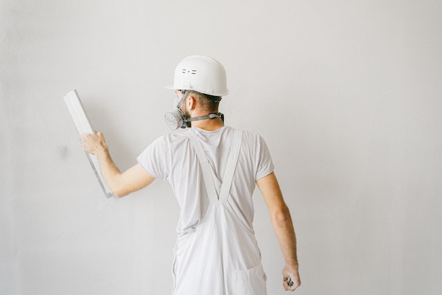 contractor in all white leveling a white wall