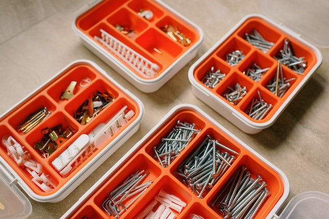 four orange tool organizing boxes filled with nails and screws and drill bits