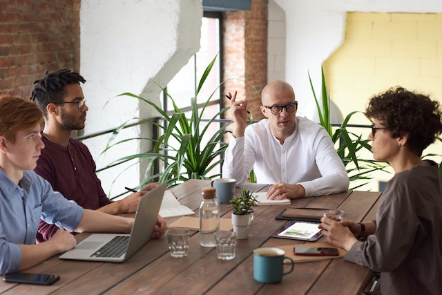 four people in a conference room discussing stats and figures in a report