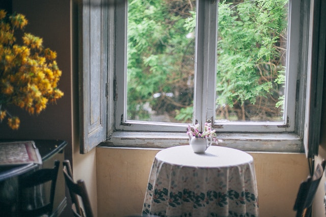 open window with cropped paint and table in front of it