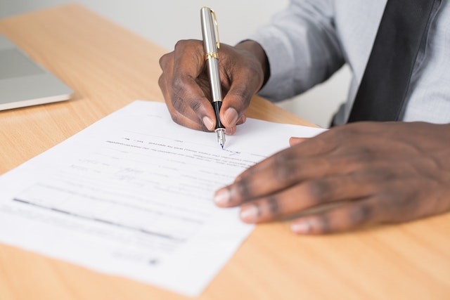 person signing lease agreement document with calligraphy pen