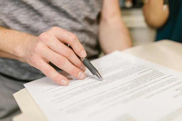 person-holding-a-pen-reading-over-documents