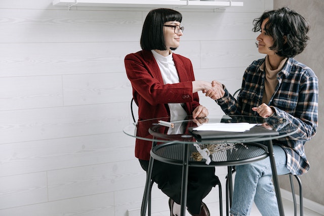 property manager in red jacket shaking hands with a tenant after a conversation