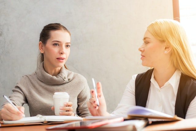 two people having a discussion while taking notes