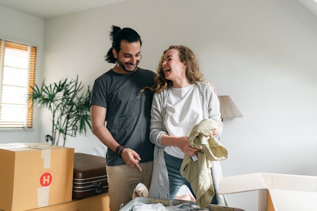 two people smiling while packing up moving boxes